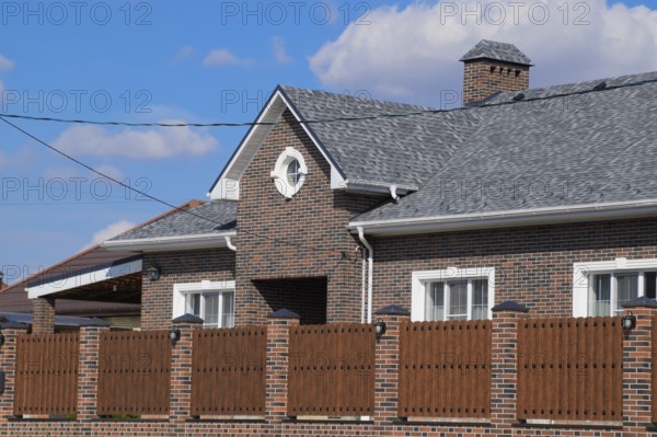 Asphalt shingle. Decorative bitumen shingles on the roof of a brick house. Atyrau, Kazakhstan