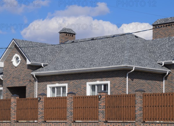 Asphalt shingle. Decorative bitumen shingles on the roof of a brick house. Atyrau, Kazakhstan