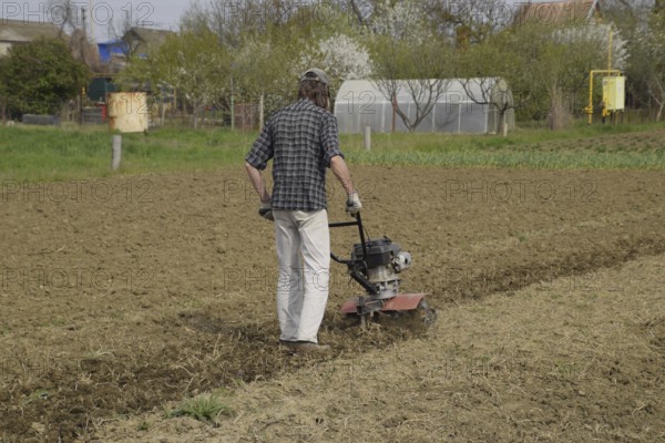 A man plows a tiller in the garden. Atyrau, Kazakhstan