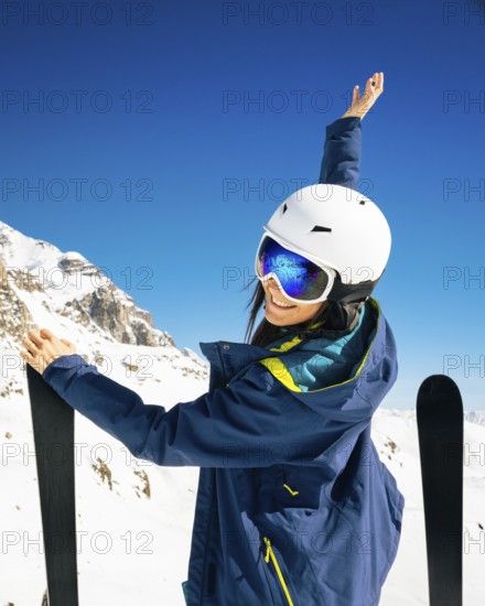 Young happy caucasian woman pose with skis arms outstretched in alpine zone. Get away skiing holidays lifestyle. Tetnuldi ski resort viewpoint. Caucasus mountains pristine high altitude freeriding