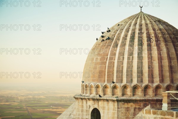 Historic dome of Ulu Cami mosque with pigeons perched, overlooking Mesopotamian plains in Mardin, southeastern Turkey heritage site