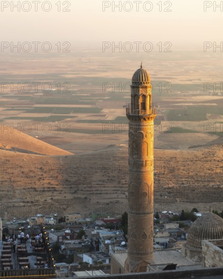Historic Ulu Cami minaret in Mardin Turkey illuminated by sunset, overlooking ancient Mesopotamian plains and Anatolian landscape