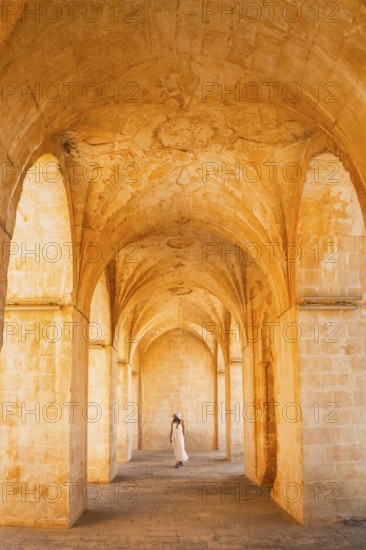 Kasimiye Medrese stone arches with traveler in white dress, iconic historic landmark in Mardin, Southeast Turkey