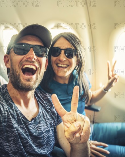 Happy casual dressed tourist taking selfie inside airplane - Cheerful couple on summer vacation - Passengers boarding on plane - Holidays and transportation concept