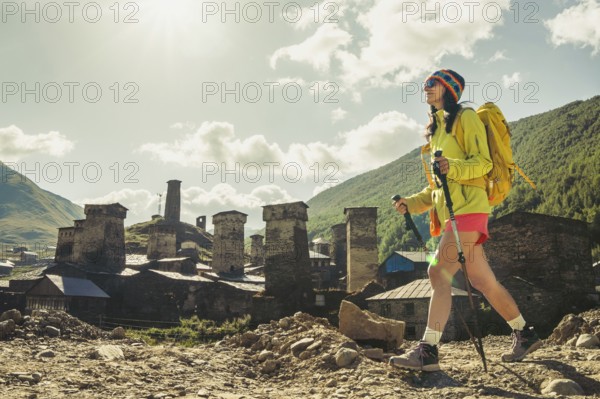 Traveler hiking with backpack and poles in Ushguli, Svaneti mountains, wellness trekking and adventure lifestyle in Caucasus