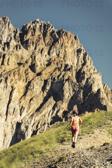 Sporty Female athlete trail runner running in motion mid air in alpine mountains, adventure fitness and endurance training in scenic landscape.Active lifestyle concept
