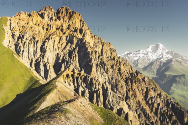 Hiker on ridge explore Kazbegi National Park in Georgia with dramatic rocky peak view Kabarjina