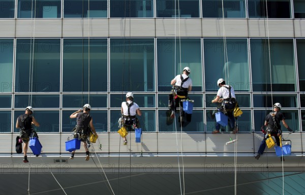 Team Of Climbing Workers In Climbing Equipment On Office Building Cleaning Windows, Vienna, Austria