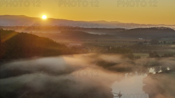 The morning dawns, the sun rises slowly over the river. A gentle mist hangs over the water and the hills are visible in the soft light. Bogen, Lower Bavaria
