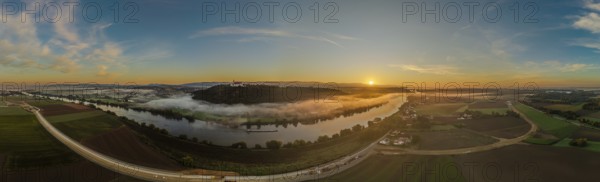 The sunrise lights up the Danube as the mist hovers over the water. Gentle hills and green fields characterise the tranquil landscape in the morning. Bogen, Lower Bavaria