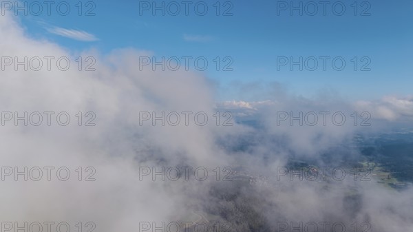 Wide clouds drift over a sunny landscape. Flat hills and part of the village are visible in the background. The scene conveys the tranquillity and beauty of nature. Roßberg, Miltach, Upper Palatinate