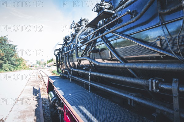 Partial view of a shiny steam locomotive showing the detailed mechanics and the railway landscape, Gera, Thuringia, Germany