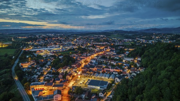 A quiet town in Germany appears at dusk. Lights from the streets glow softly while the surrounding hills are visible in the background. Bogen, Lower Bavaria