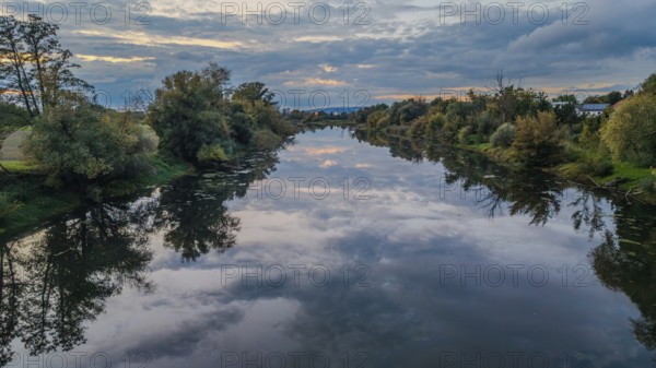A calm river landscape at dusk shows trees and clouds in the reflecting water surface. Nature appears peaceful and inviting. Bogen, Lower Bavaria