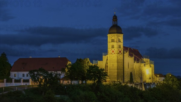 The pilgrimage church of the Assumption of the Virgin Mary on the Bogenberg has a golden light in the evening that emphasises its beauty. Surrounded by trees and buildings, it presents itself in a peaceful atmosphere. Bogen, Lower Bavaria