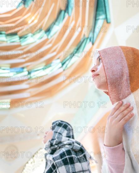 Muslim young millenial girls with scarfs during the pray in modern Marmara mosque in Istanbul. Turkey