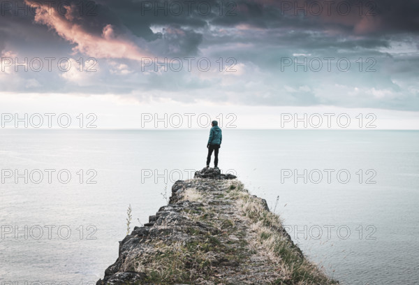 Male person standing on edge of Tsikhisdziri fortress ruins in Tsikhisdziri village in Georgia with black sea background