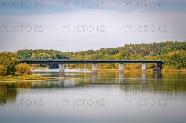 Bridge over a quiet reservoir with wooded shores and clear skies, Zeulenrodaer Meer reservoir, Zeulenroda-Triebes, Thuringia, Germany