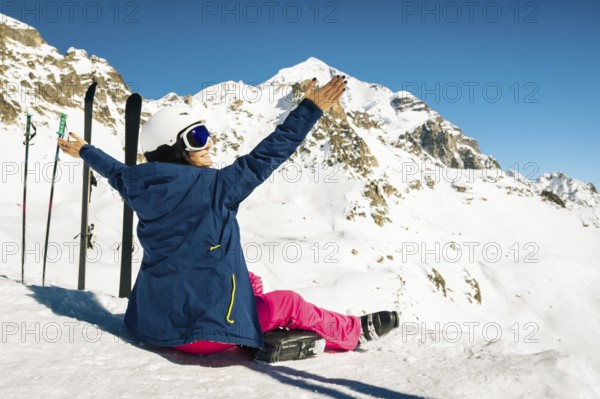 Young happy caucasian woman pose with skis arms outstretched in alpine zone. Get away skiing holidays lifestyle. Tetnuldi ski resort viewpoint. Caucasus mountains pristine high altitude freeriding
