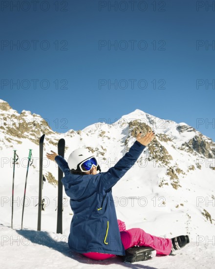 Young happy caucasian woman pose with skis arms outstretched in high mountains. Get away skiing holidays lifestyle. Tetnuldi ski resort viewpoint. Caucasus mountains pristine high altitude freeriding