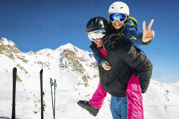 Young happy caucasian couple portrait together piggyback hug enjoying looking at camera in snowy caucasus mountains in winter. Get away skiing holidays lifestyle. Tetnuldi ski resort top viewpoint