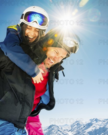 Romantic happy skiers couple in love having fun together playing in mountains piggybacking at wintertime.Winter lovers couple isolated mock up outdoors blue banner copy space background