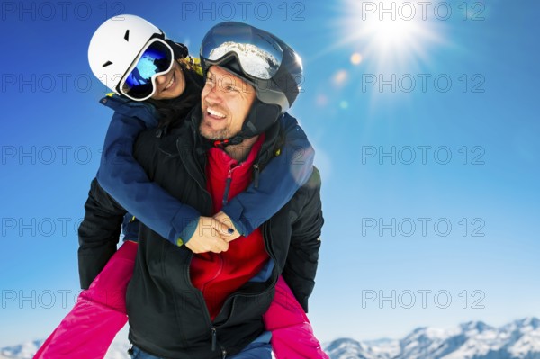Romantic happy skiers couple in love having fun together playing in mountains piggybacking at wintertime.Winter lovers couple isolated mock up outdoors blue banner copy space background