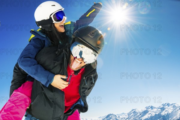 Romantic happy skiers couple in love having fun together playing in mountains piggybacking at wintertime.Winter lovers couple isolated mock up outdoors blue banner copy space background
