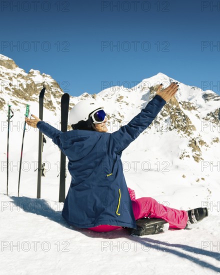 Young happy caucasian woman pose with skis arms outstretched in alpine zone. Get away skiing holidays lifestyle. Tetnuldi ski resort viewpoint. Caucasus mountains pristine high altitude freeriding