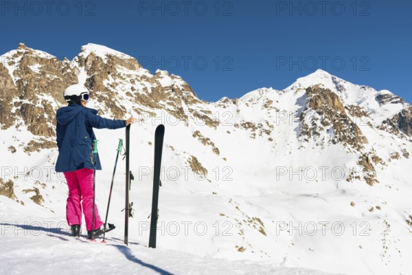 Young caucasian woman pose looking at snowy mountains range in winter. Get away skiing holidays lifestyle. Tetnuldi ski resort viewpoint. Caucasus mountains pristine high altitude freeriding