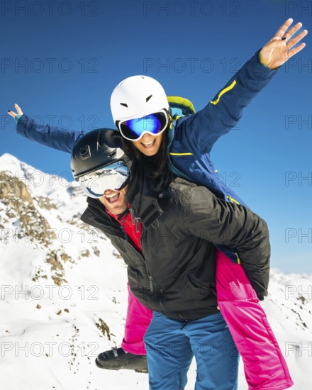 Happy young caucasian skiers couple in love having fun together playing in mountains piggybacking at wintertime. Couple ski isolated mock up outdoors blue winter banner copy space background