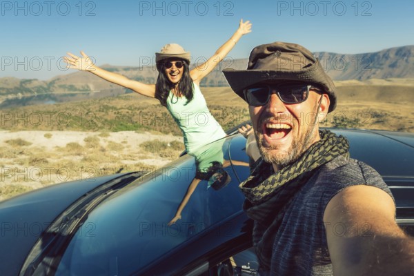 Happy travelers taking selfie photo on summer road trip with rented car in Turkey, symbolizing freedom, travel insurance, car hire lifestyle, and holiday adventure. Nemrut crater travel destination