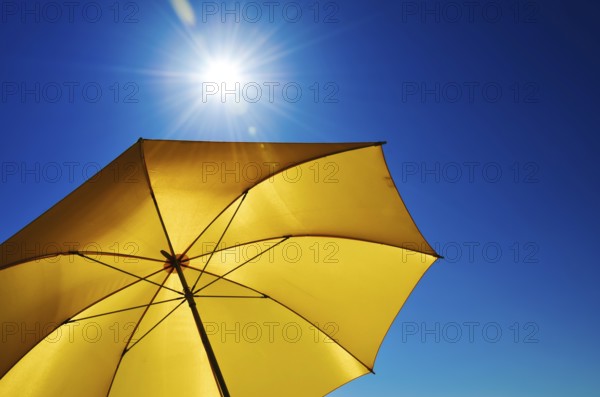 Open Yellow Umbrella with Bright Sun and Blue Sky