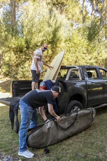 Two men packing surfboards into a truck