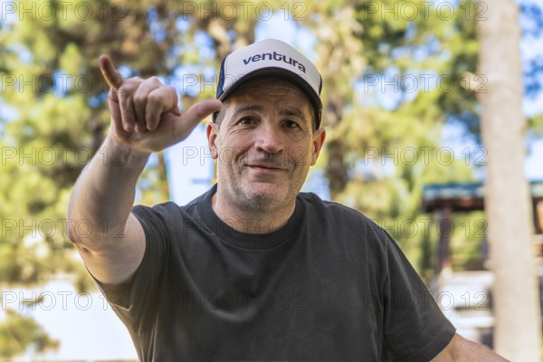Surfer in a cap making a hang loose gesture