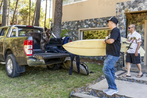 Men and a dog getting ready for a surf trip