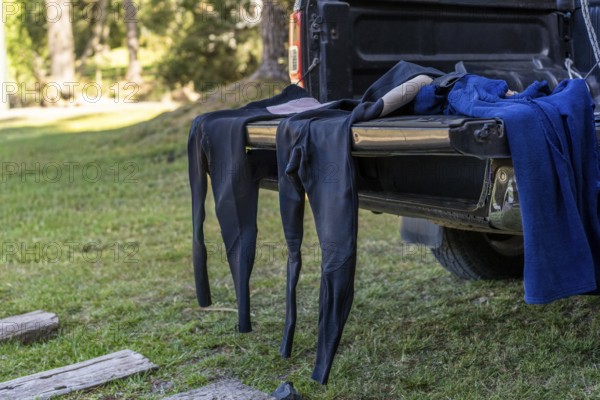 Surf wetsuit and gear drying on a pickup truck