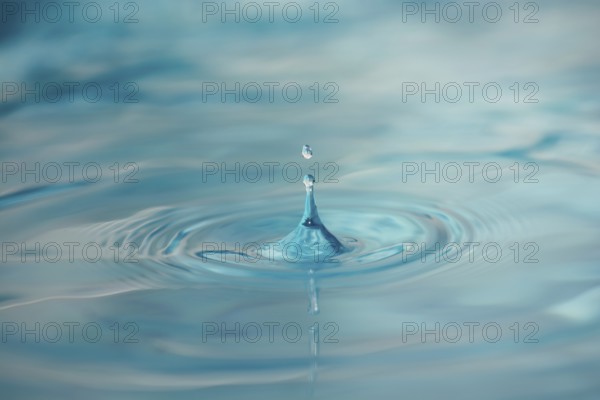 Water Drop Creates Circular Waves on Calm Surface Of Blue Water