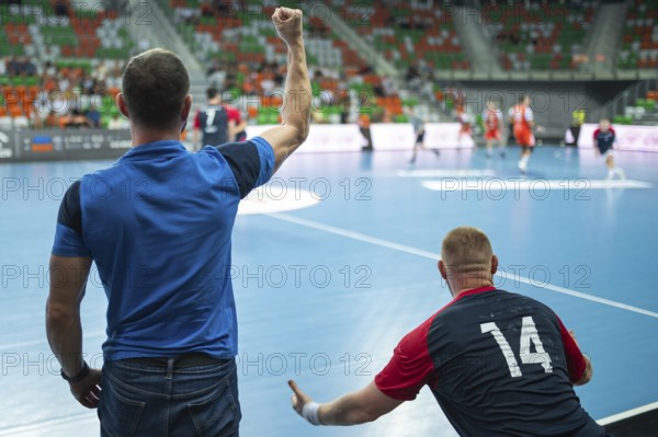 View form the behind on head coach and substitutions bench with handball match in background. Lubin, Poland
