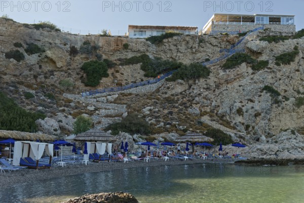 Secluded Grande Blue Beach with blue parasols and clear sea water, Grande Blue Beach, Stegna, Archangelos, Rhodes Island, Greece