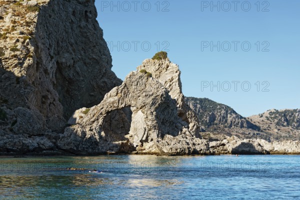Stone arch at Grande blue beach with clear blue water and sunny sky, showing a natural and peaceful landscape, Grande Blue Beach, Stegna, Archangelos, Rhodes Island, Greece