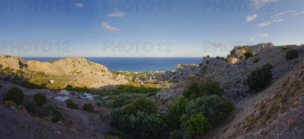 Panoramic view of the hilly coastal landscape of Stegna with clear blue sky and natural vegetation, Grande Blue Beach, Stegna, Archangelos, Rhodes Island, Greece