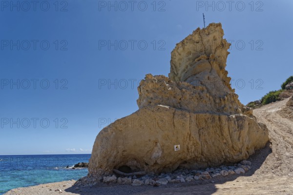 An impressive rock formation on Grande Blue Beach with clear blue sky and sea in the background, Grande Blue Beach, Stegna, Archangelos, Rhodes Island, Greece