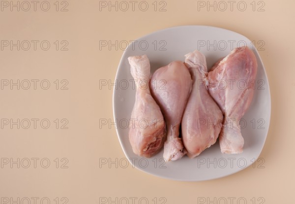 Chicken legs on a plate ready for cooking broth, copy space