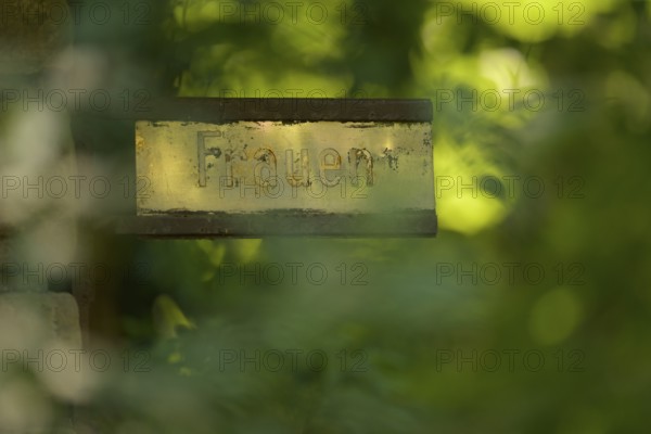 Old gilded sign with the inscription Women, weathered and surrounded by green vegetation, Ggenlicht, Rombergpark, Dortmund, North Rhine-Westphalia, Germany