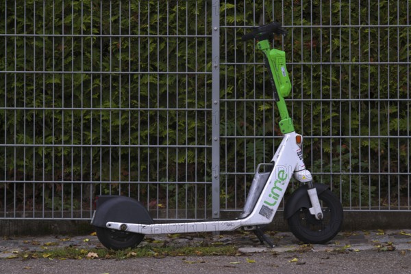 On the side of the road, fence, parked e-scooter, electric scooter, scooter, in the bike rental of the company Lime, OnLime and Uber, Stuttgart, Baden-Württemberg, Germany