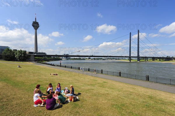 Ladies picnic on the Rhine promenade, view of the Rhine Tower, TV Tower, and Rheinknie Bridge, Düsseldorf, Rhineland, North Rhine-Westphalia, Germany
