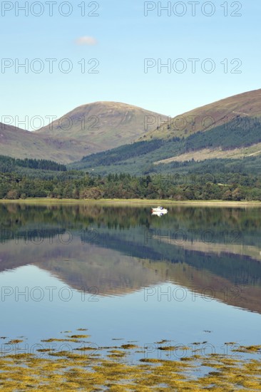 A peaceful body of water reflecting the surrounding mountains and a clear blue sky, Loch Eil, Scotland, United Kingdom