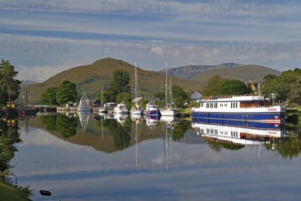 Water reflections of boats in the harbour in front of picturesque mountains, Caledonian Canal, Banavie, Fort William, Scotland, Great Britain