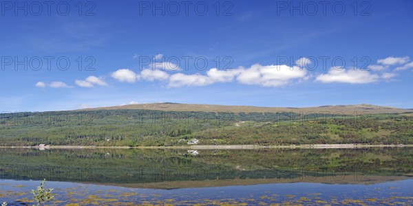 A clear lake reflects the surrounding mountains and cloudy sky, Caledonian Canal, Fort William, Scotland, United Kingdom
